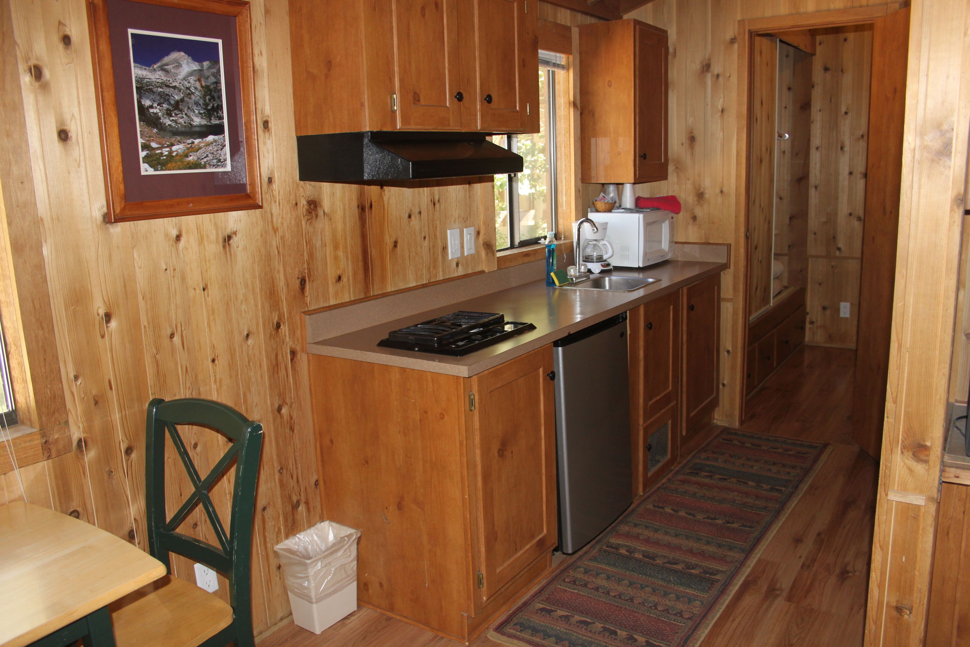 Eine Holzhütte mit einer Küche, ausgestattet mit Herd, Spüle und Kühlschrank.