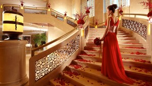 A grand staircase with a woman in a red dress, surrounded by rose petals. - Grand New Century Hotel Canal Hangzhou (Hangzhou)