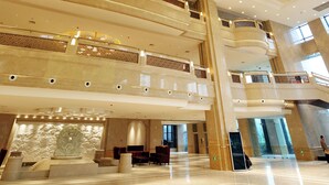 A spacious lobby with a large chandelier, multiple floors, and a central sculpture. - Grand New Century Hotel Canal Hangzhou (Hangzhou)