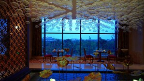 A room with a large window, a patterned wall, and a table with chairs. - Grand New Century Hotel Canal Hangzhou (Hangzhou)
