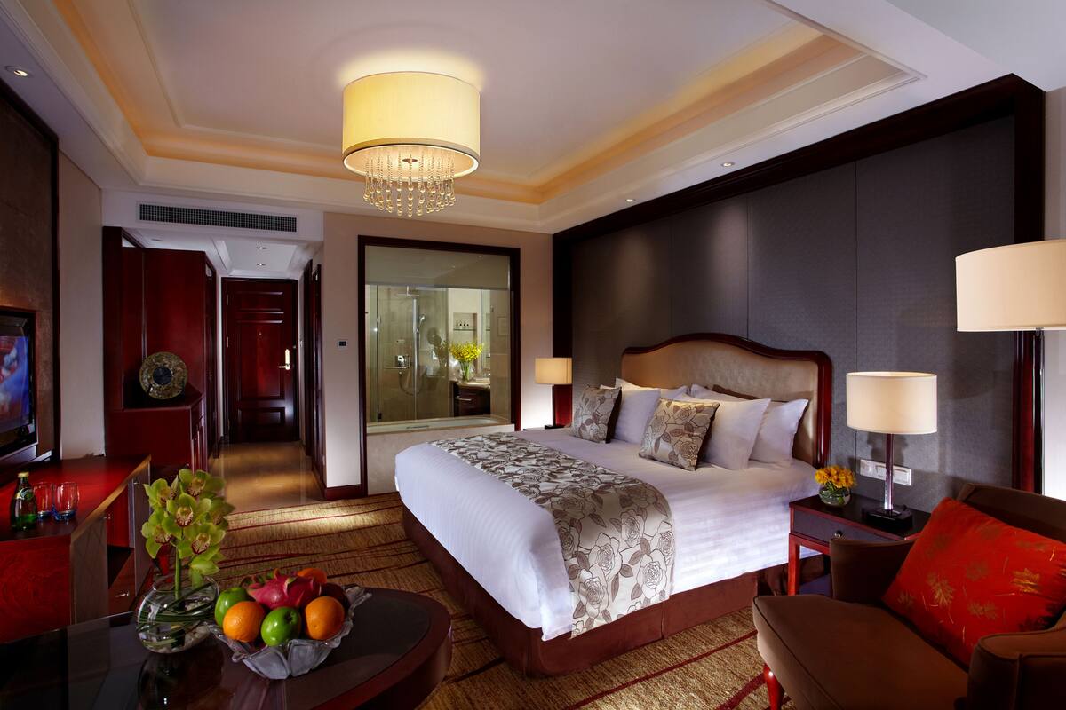 Ein Hotelzimmer mit einem großen Bett, einer Sitzecke inklusive Couchtisch und einem Fernseher.