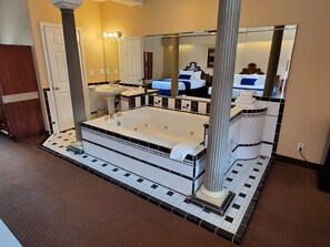 A bathroom with a large bathtub, a sink, and a mirror.