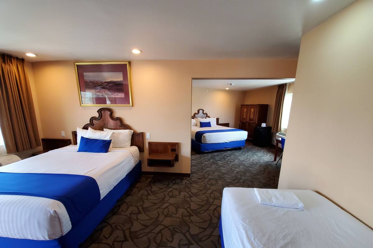 A hotel room with two beds, a large mirror, and a carpeted floor.