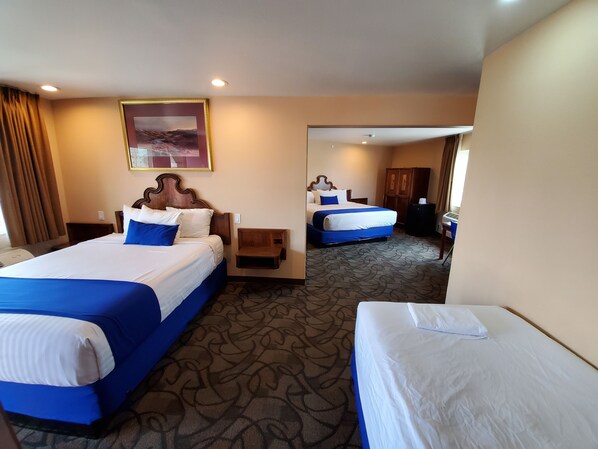 A hotel room with two beds, a large mirror, and a carpeted floor.