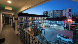 A motel with a balcony, a parking lot, and a neon sign. - Colony Inn (North Hollywood)