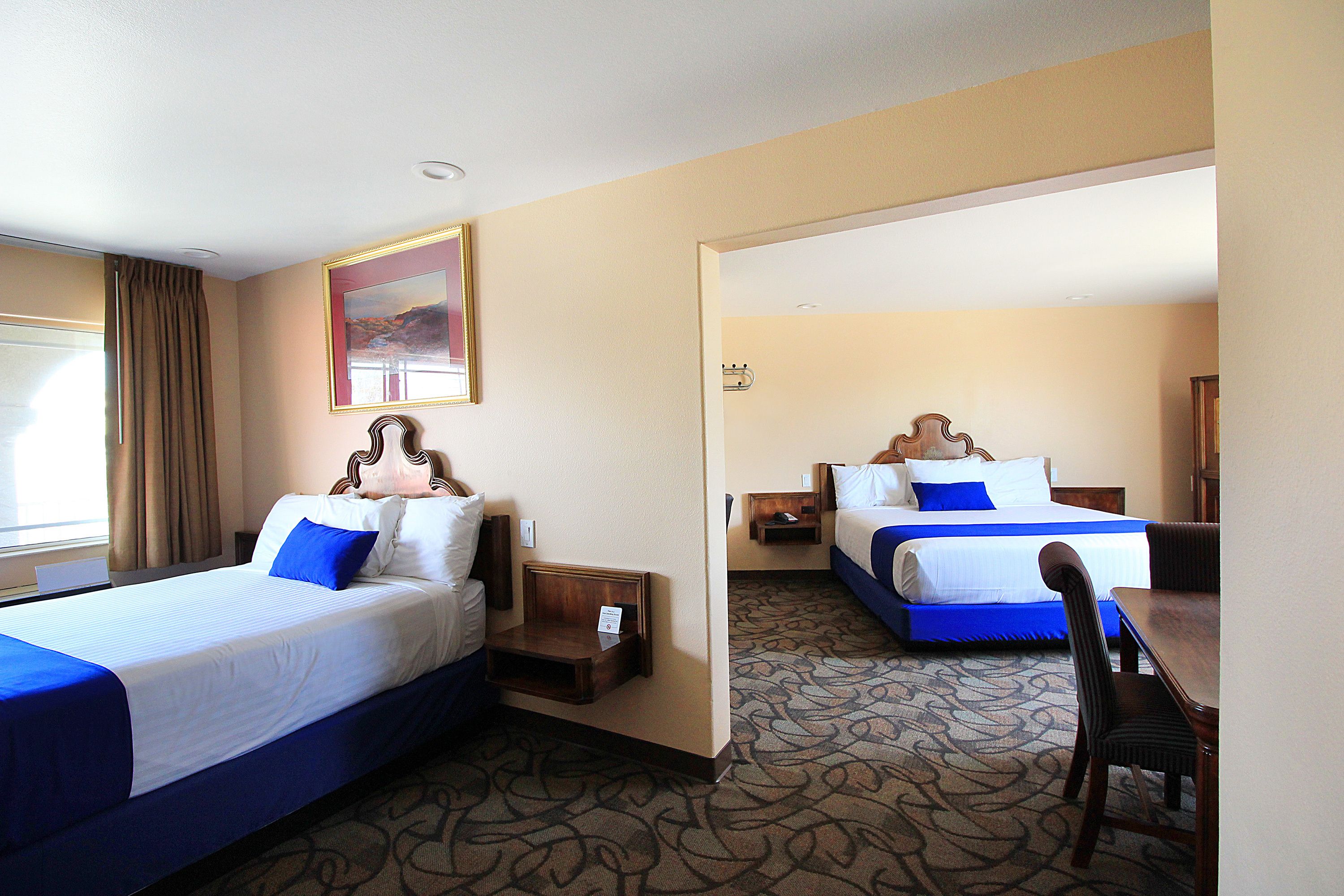 A hotel room with two beds, a desk, and a chair.