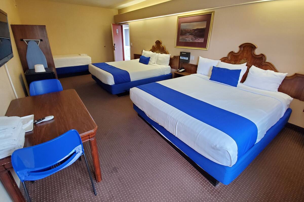 A hotel room with two beds, a desk, a chair, and a nightstand.