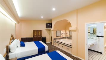 Habitación de hotel con dos camas, un baño con bañera y una televisión.