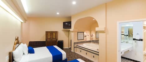 A hotel room with two beds, a bathroom with a bathtub, and a television.