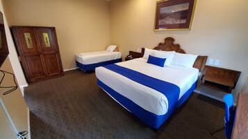 Quarto de hotel com duas camas, um guarda-roupa de madeira, um quadro pendurado na parede e chão coberto por carpete.