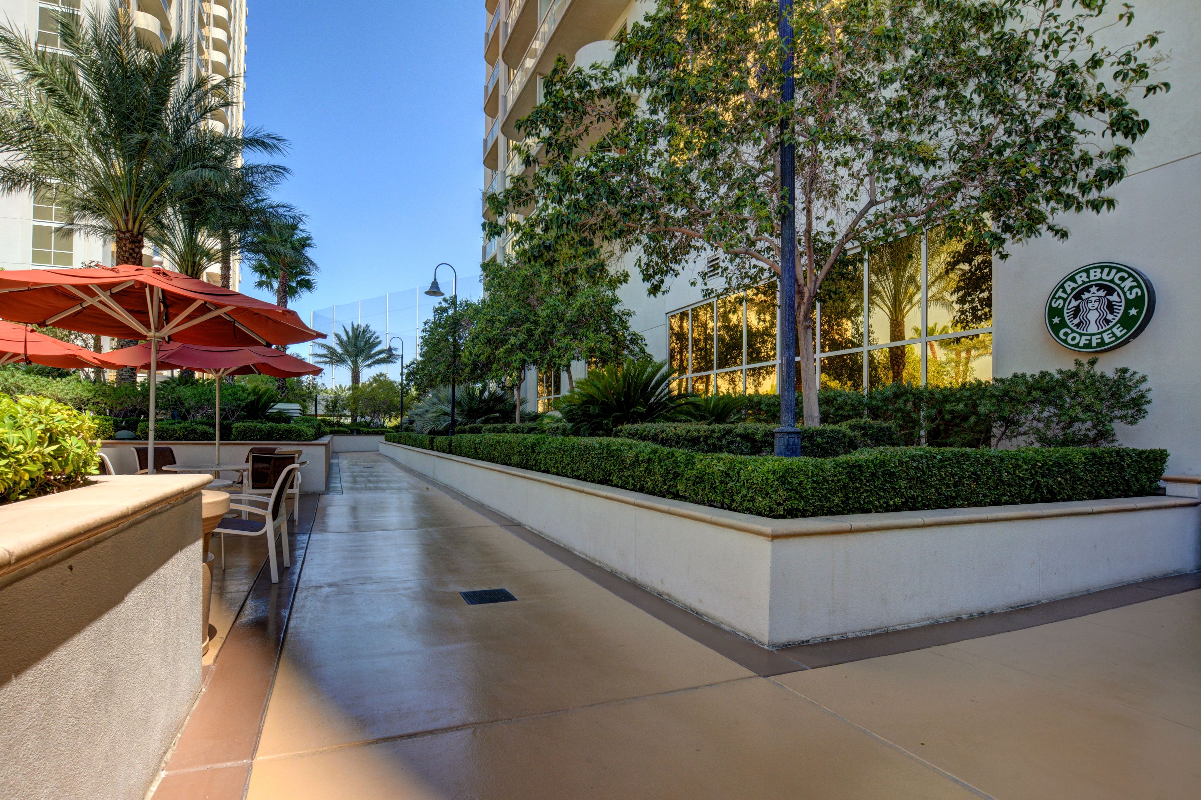 A hotel corridor with outdoor seating, palm trees, and a Starbucks sign.