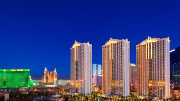 Un hotel di grandi dimensioni con numerosi piani, un casinò ben visibile sullo sfondo e un moderno skyline urbano illuminato.