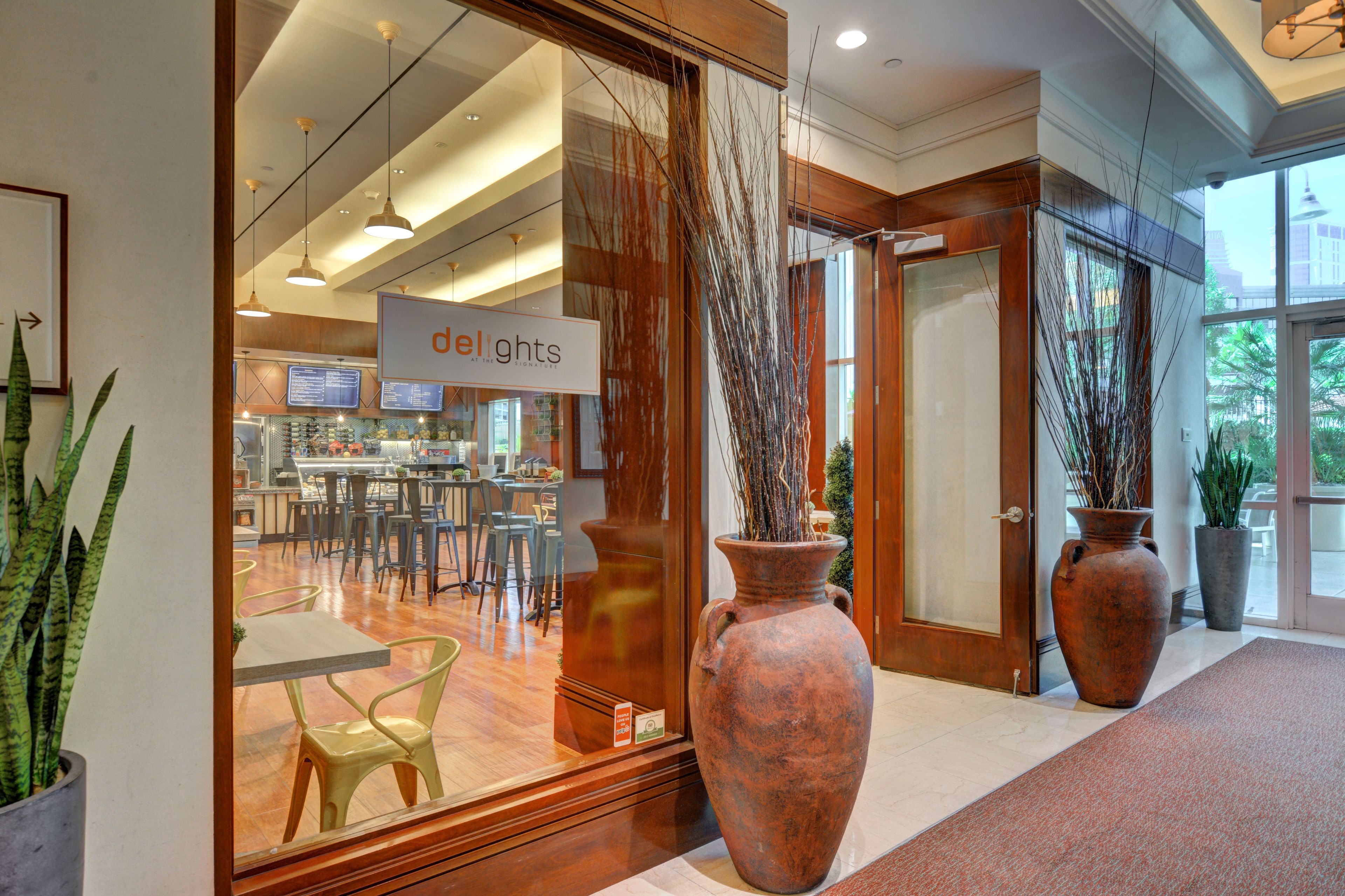 A modern interior with a reception area, large vases, and a dining area with chairs and tables.