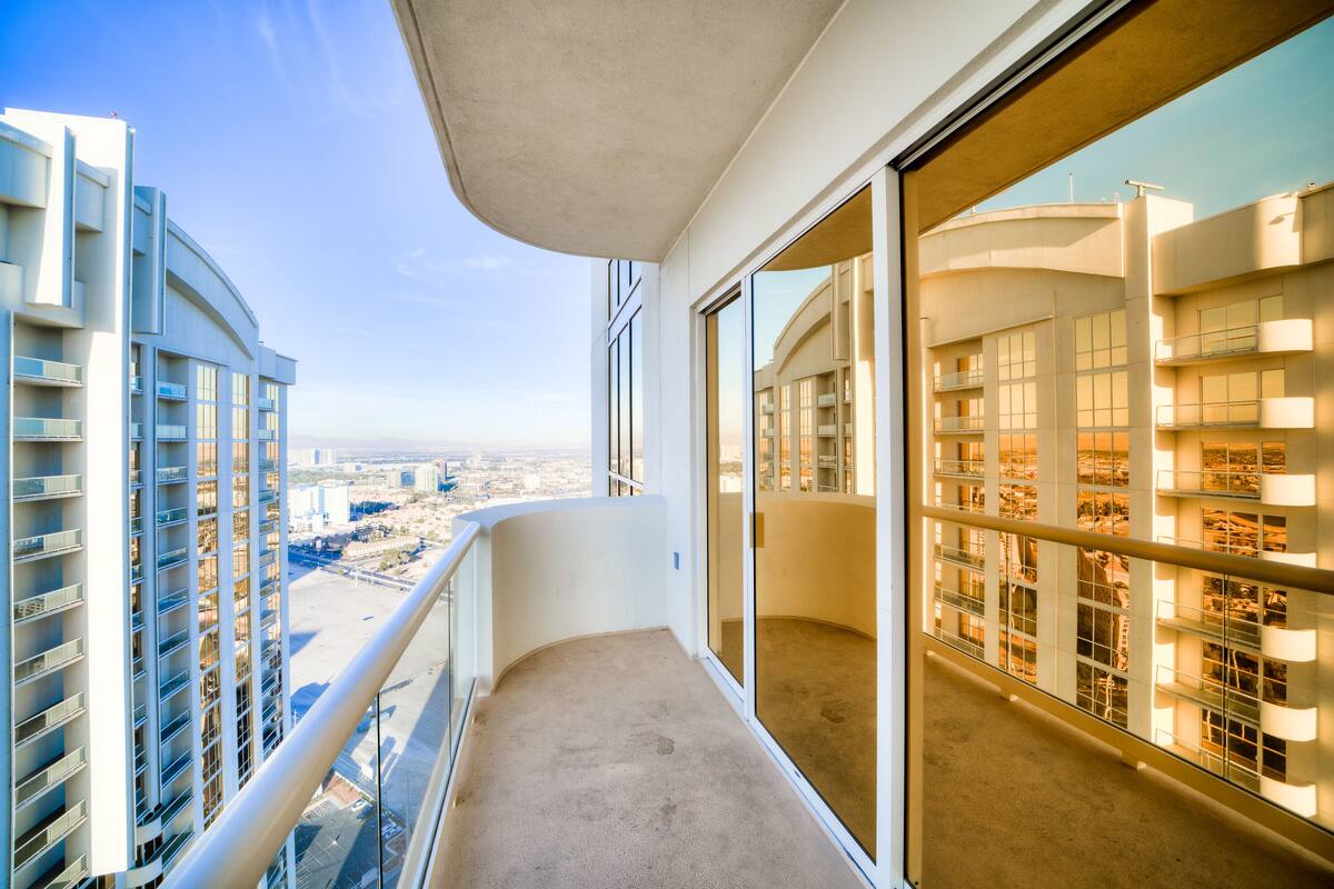 Un balcón en un edificio alto con vista despejada al paisaje urbano, que presenta arquitectura moderna y un área de balcón amplia.
