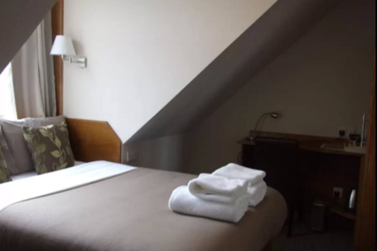 A hotel room with a bed, a desk, and a lamp.