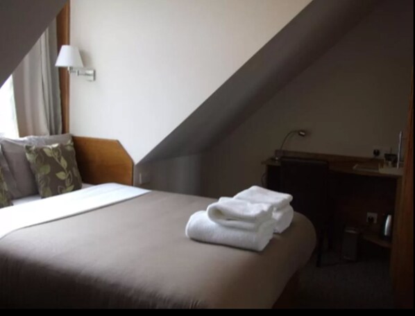 Ein Hotelzimmer mit Bett, Schreibtisch und Lampe.