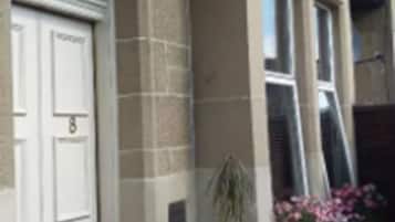A house with a white door, a window, and a potted plant.