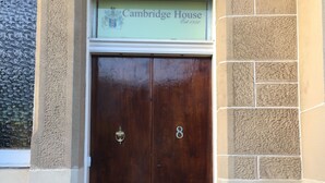 A double wooden door with the number 8, a plaque reading "Cambridge House Est. 1880", and a textured wall to the left. - Cambridge House (Edinburgh)