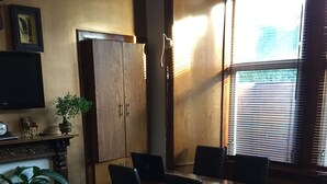 A conference room with wooden tables and chairs, a potted plant, and a large window with blinds. - Cambridge House (Edinburgh)