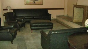 A living room with a black sofa, two armchairs, a coffee table, and a fireplace.