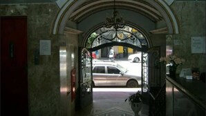 An entrance with a red door, a chandelier, and a view of a street with cars.