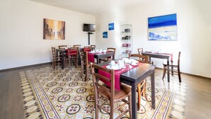 A dining area with multiple tables and chairs, a patterned floor, and artwork on the walls. - B&B Alma (Lucca)