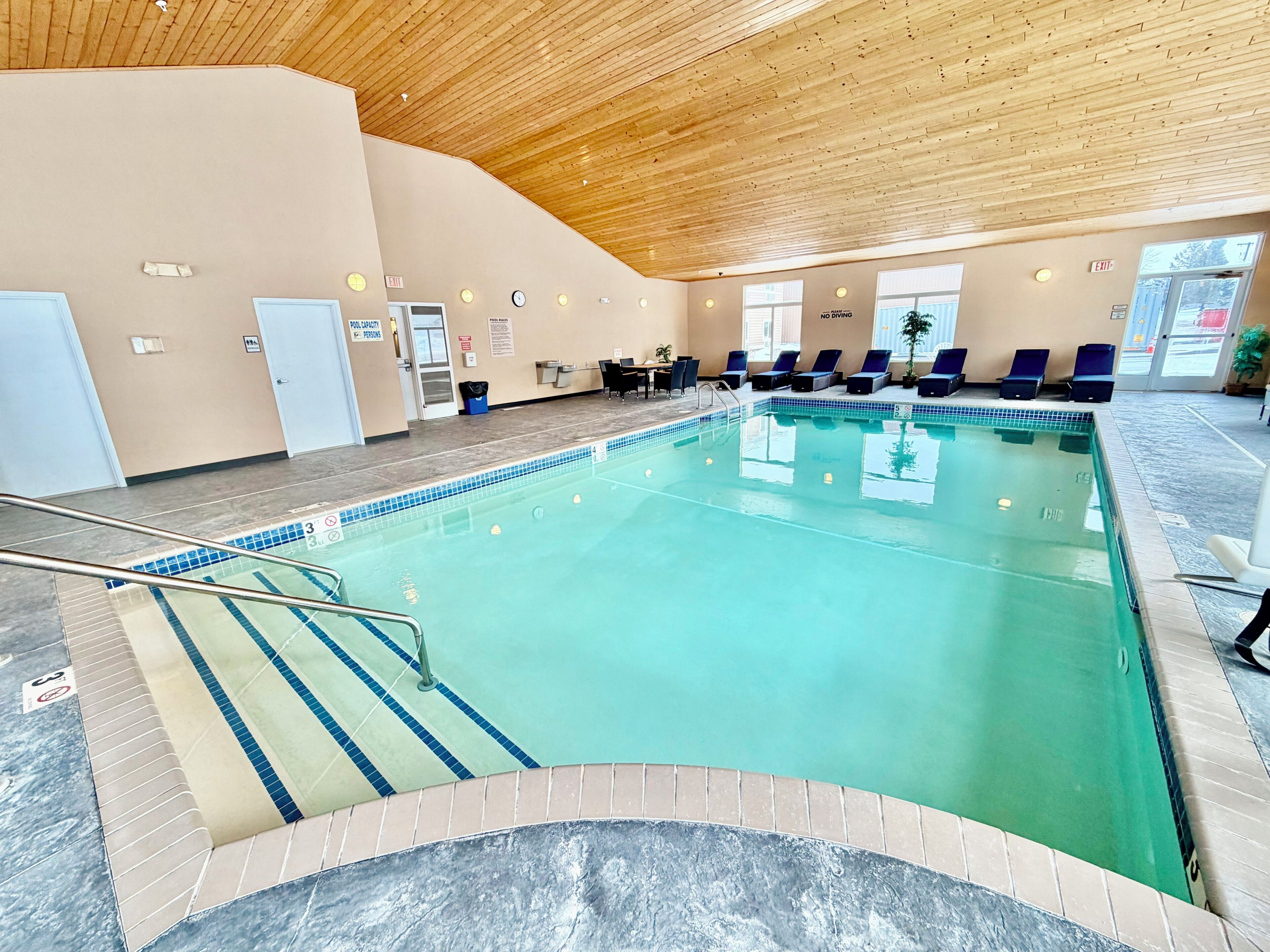 Una piscina interior amb sostre de fusta, gandules i zona de bany.