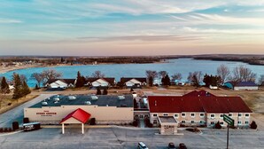 Ein Hotel mit rotem Dach, Parkplatz und Blick auf einen See.