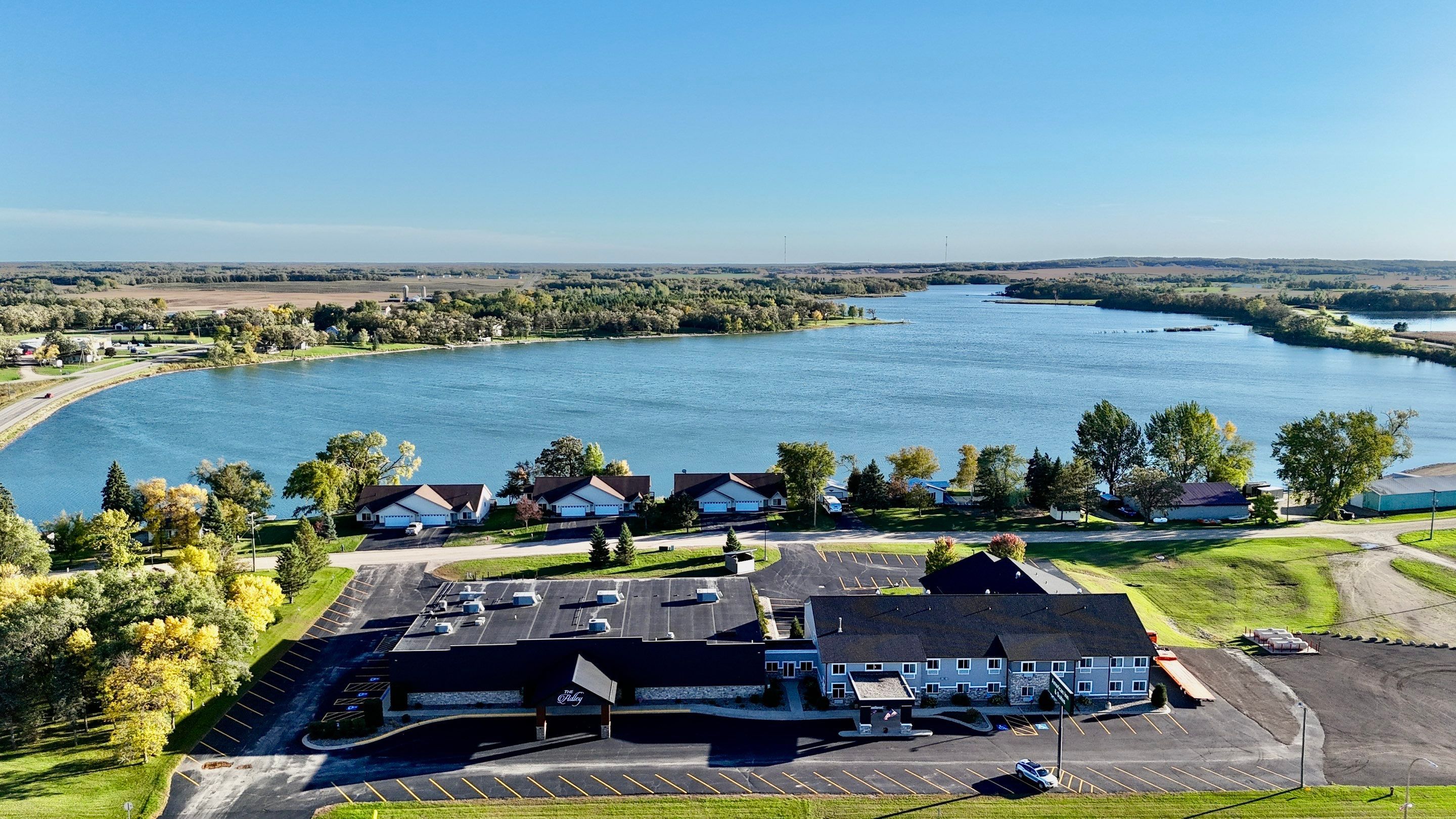 Un hôtel situé au bord du lac, doté d’un parking, d’un bâtiment avec une enseigne et offrant une vue sur le lac.