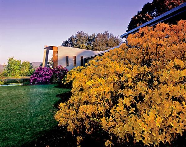 A modern house with a sloped roof, surrounded by a well-maintained lawn and vibrant autumn foliage. - Panorama Retreat & Resort (Kalorama)