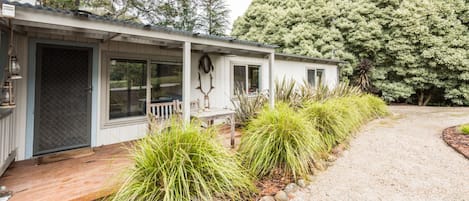 A single-story house with a covered porch, a gravel driveway, and a well-maintained garden with tall grasses.