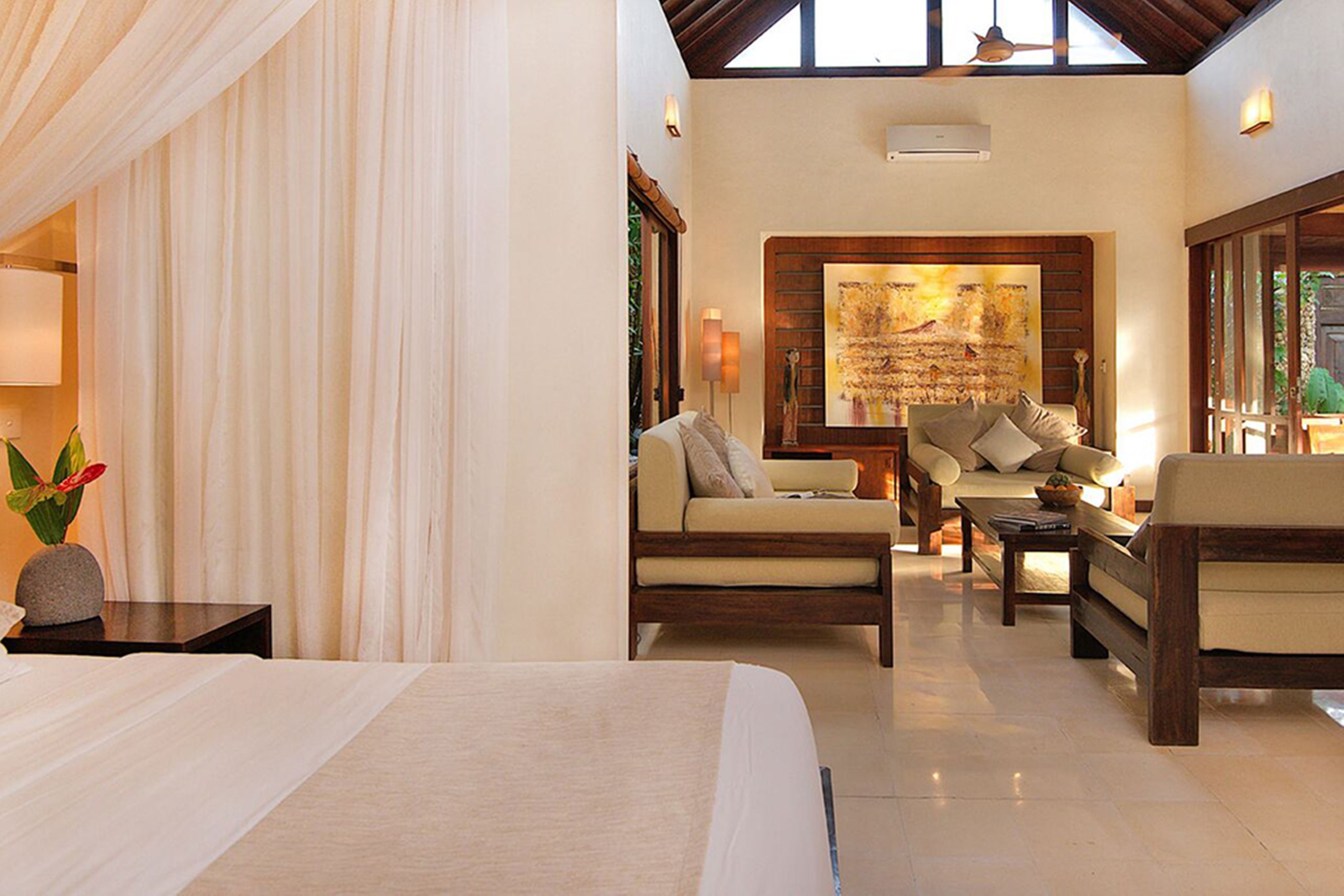 A spacious room with a large bed, two sofas, a coffee table, and a painting on the wall.