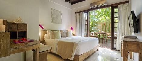 A hotel room with a bed, a desk, a TV, and a view of the outdoors.