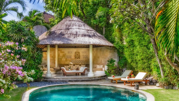 A poolside area with a thatched-roof structure, lounge chairs, and a well-maintained lawn. - Villa Kubu, Seminyak (Seminyak)
