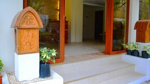 A wooden decorative panel with intricate carvings, a potted plant, and a set of steps leading to a glass door. - The Sitio Boracay Villas and Suites (Boracay Island)