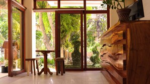 A spacious room with large glass doors leading to a garden, a wooden bench, and a small table. - The Sitio Boracay Villas and Suites (Boracay Island)