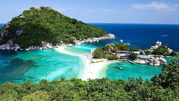 A tropical island with a small beach, clear turquoise waters, and lush greenery. - Save Bungalows (Koh Tao)