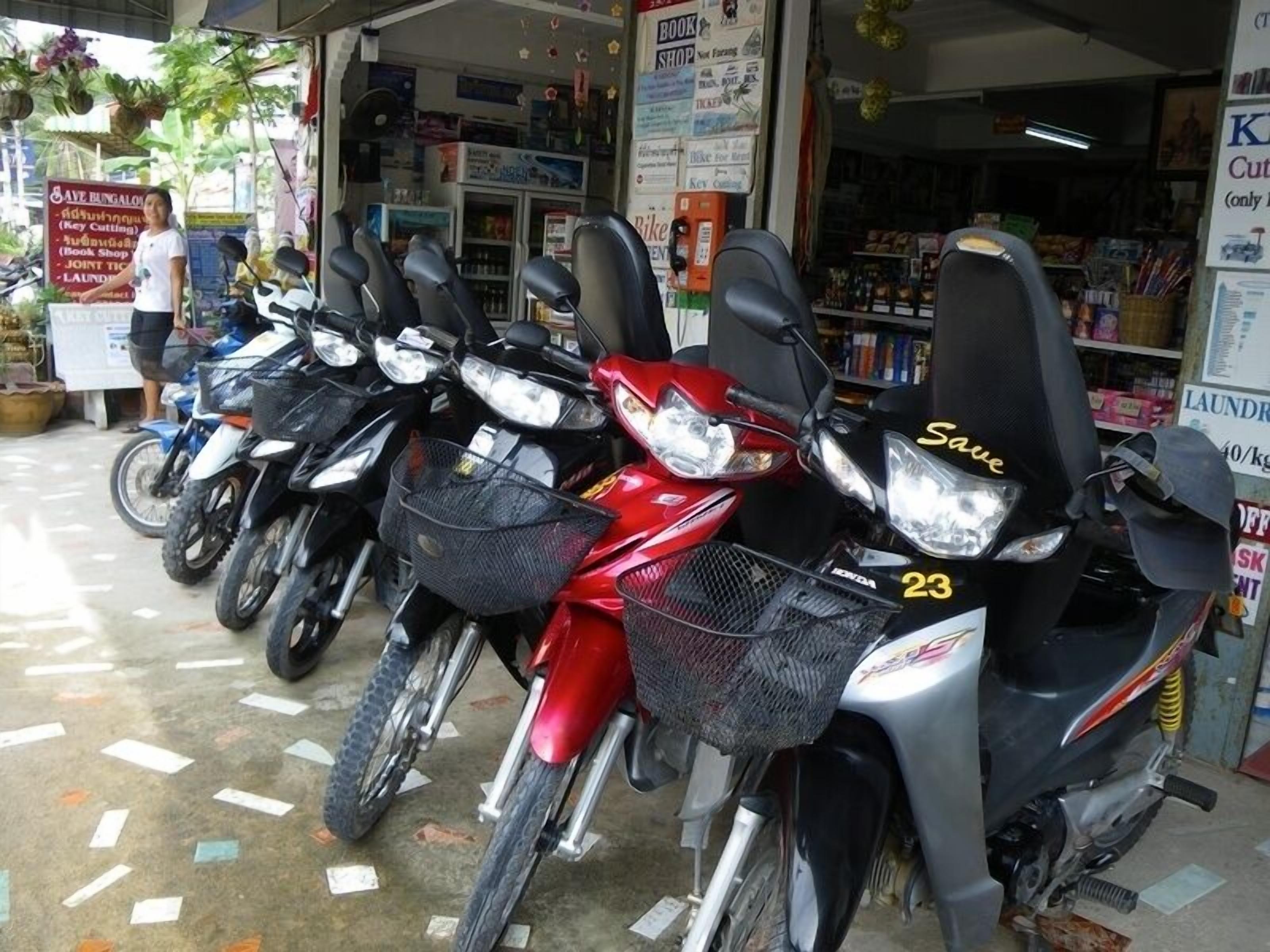 Una fila de motocicletas estacionadas frente a una tienda con un letrero que anuncia servicios como corte de libros y lavandería.