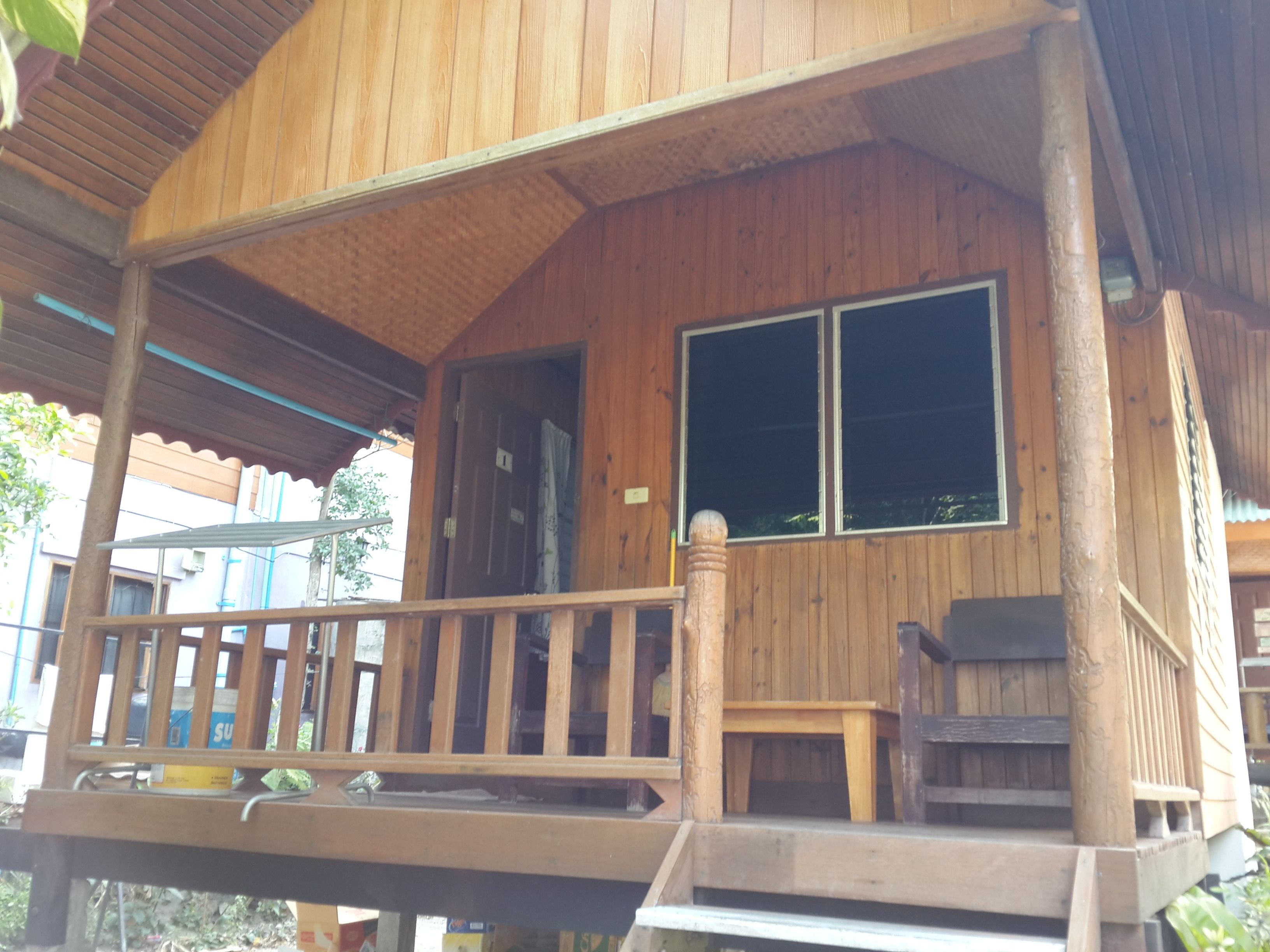 Una cabaña de madera con un porche, una mesa pequeña y un banco.