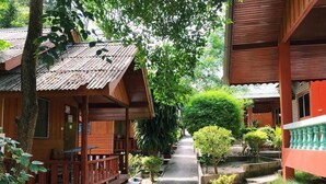 A wooden building with a tiled roof, surrounded by greenery and a pathway. - Save Bungalows (Koh Tao)