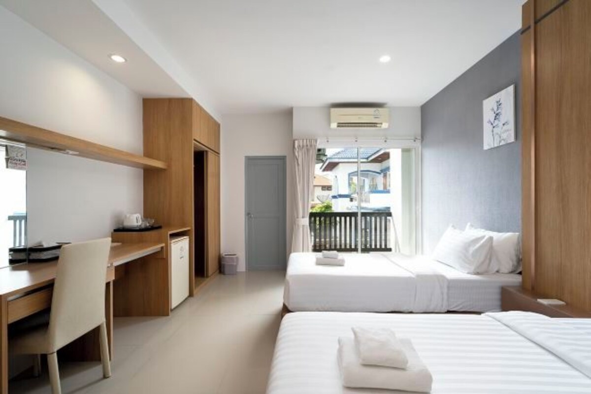 A modern hotel room with two beds, a desk, and a balcony.