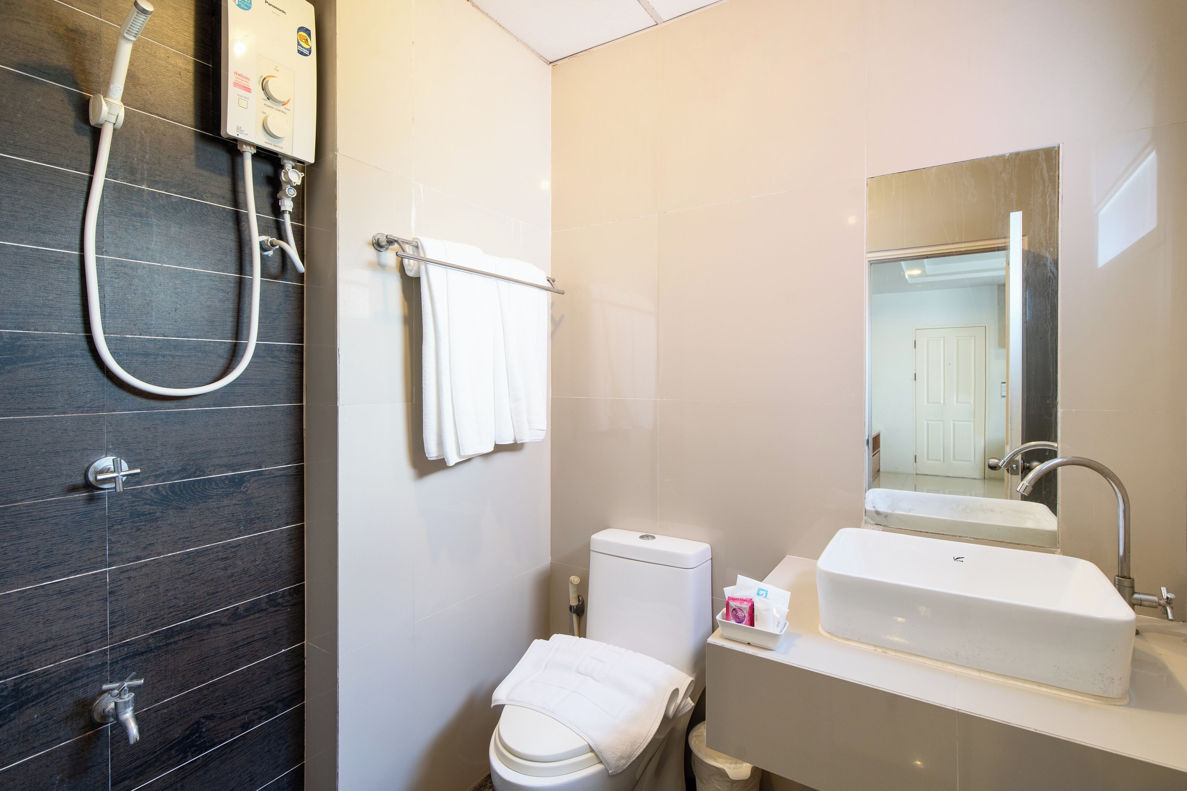 A bathroom with a shower, toilet, sink, and a mirror.