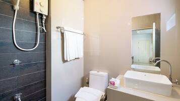 A bathroom with a shower, toilet, sink, and a mirror.