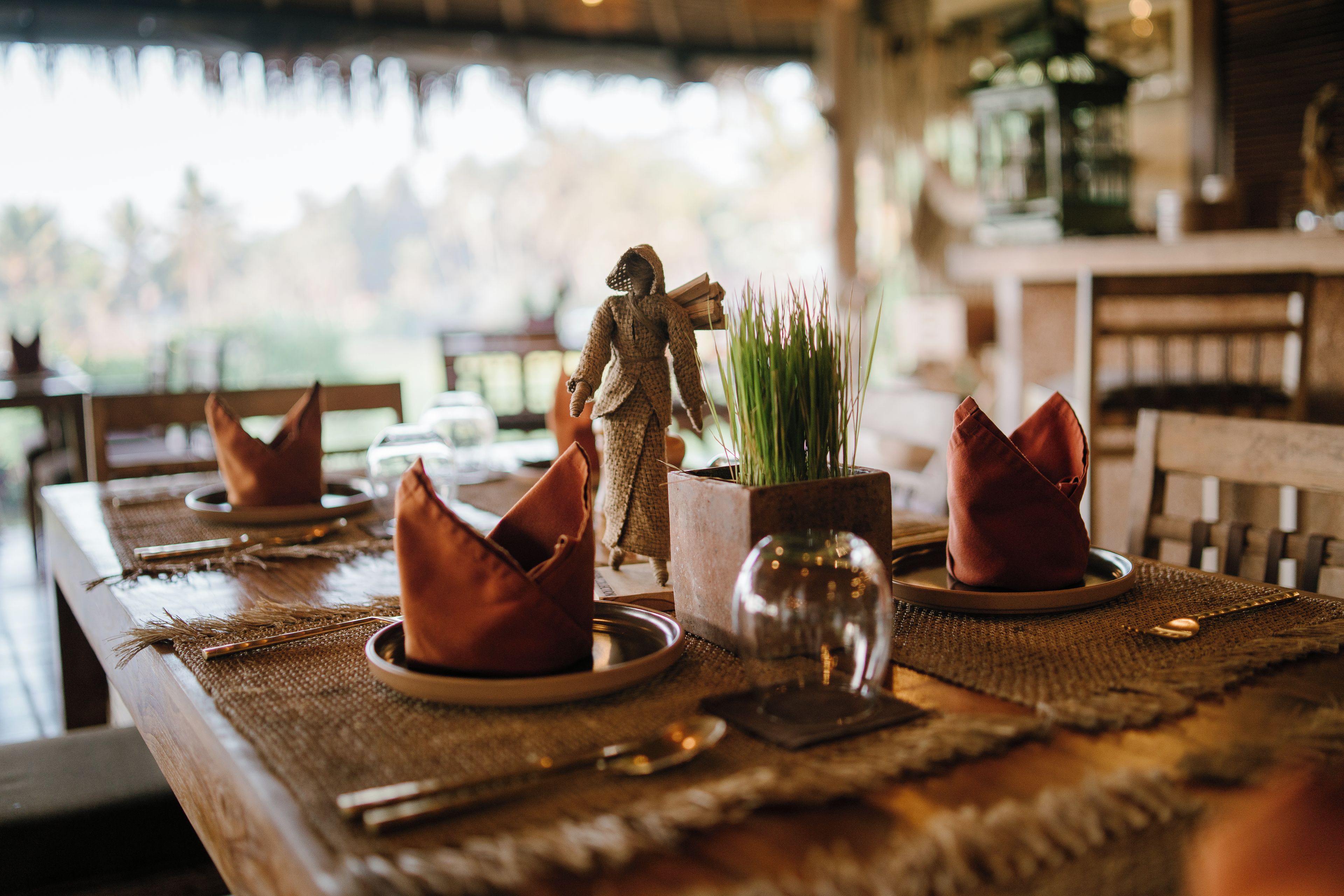 Una mesa de comedor dispuesta con platos, cubiertos y adornos.