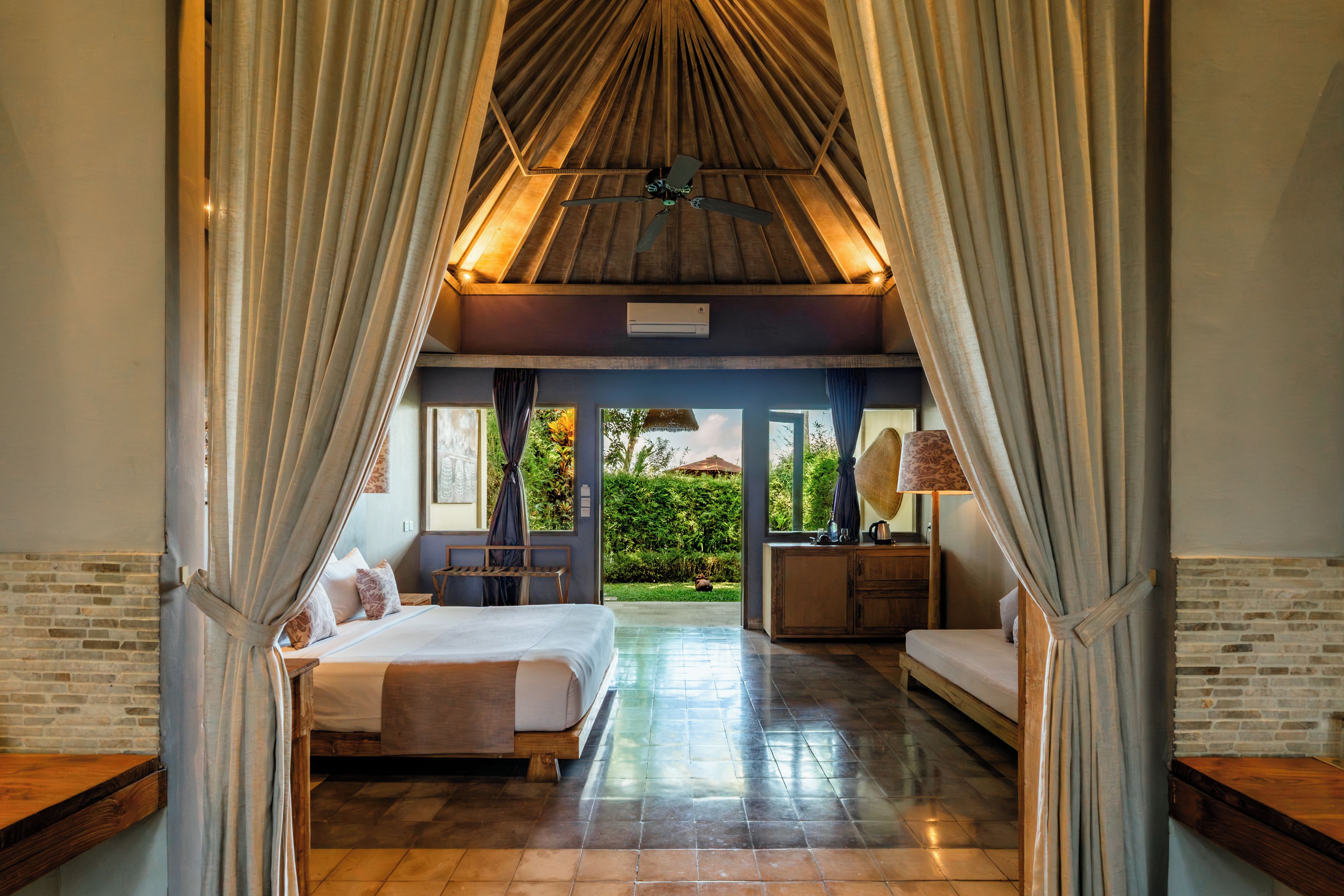 Habitación de hotel con cama, escritorio, silla y vista al jardín.