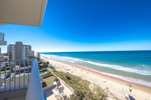 A beachfront hotel with a view of the ocean, a pool, and a patio area with outdoor furniture. - Beachside Tower (Main Beach)