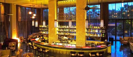 A bar area with a curved counter, multiple seating options, and a view of the outdoors through large windows.