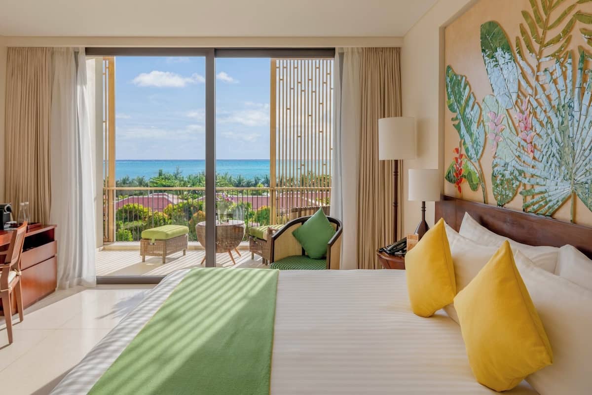 Ein Hotelzimmer mit Bett, Schreibtisch, Stuhl und einem Balkon mit Meerblick.