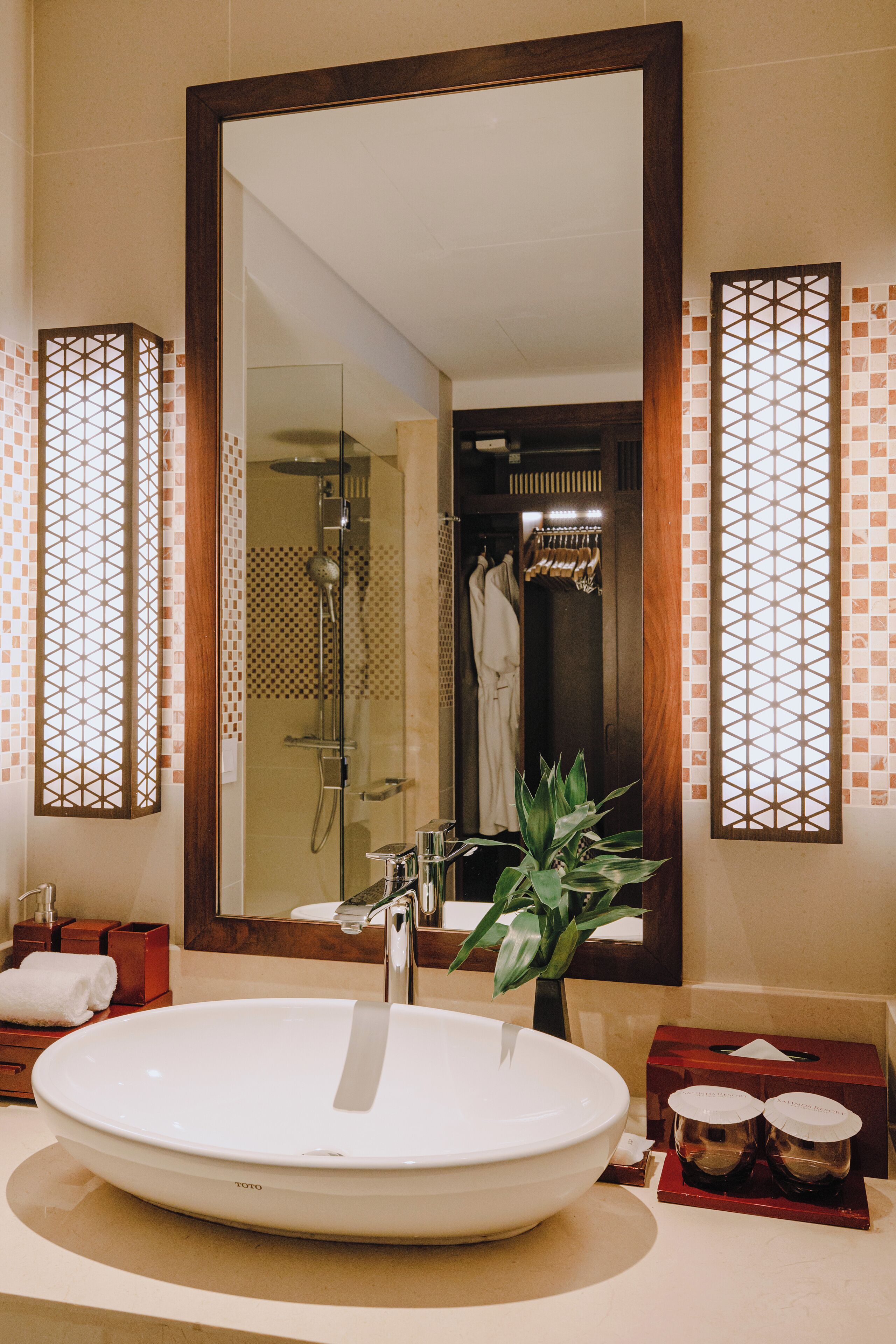 Ein Badezimmer mit einem großen Spiegel, einem weißen Waschbecken, einer Dusche und einem Handtuchhalter.