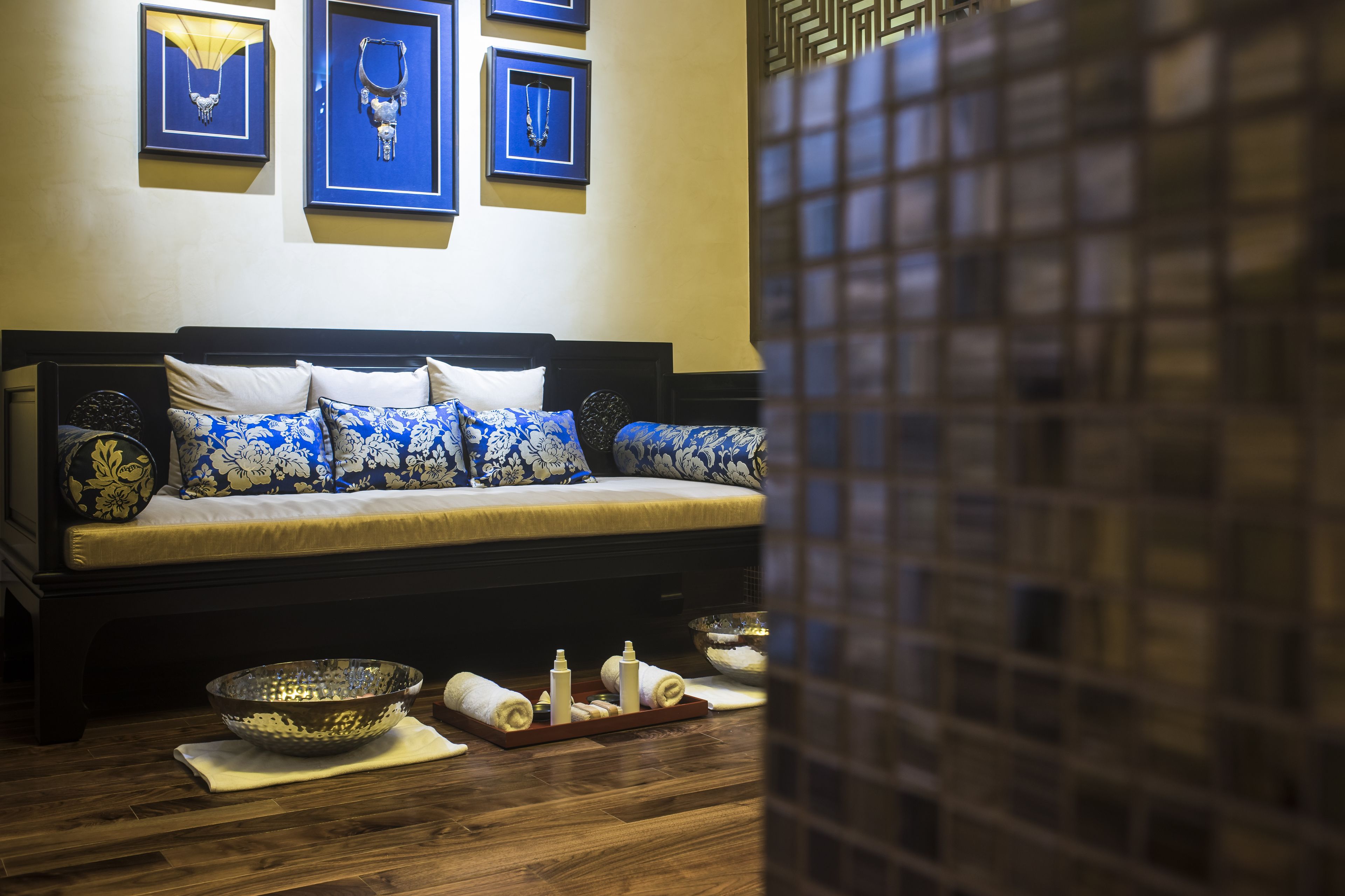 A room with a bed, framed jewelry, and a tiled wall.